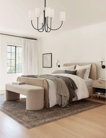 #color::buff #color::cream-boucle | The Mikhail cream boucle foam-padded bench sits in a bedroom at the end of a bed with a natural woven bed frame and underneath a black chandelier pendant.