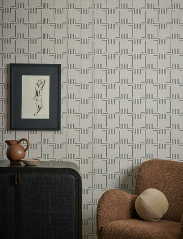 #color::natural | Mesa Grasscloth Wallpaper by Élan Byrd on a wall behind and accent chair and sideboard cabinet.