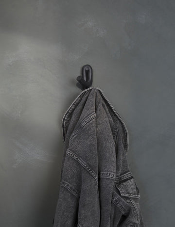 #color::black | Black Leggy Crossed Wall Hook by SIN Ceramics with a black jean jacket hanging on it