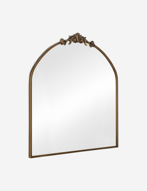 Angled view of the Tulca arched gold mirror with flat bottom edge and traditional scroll detailing.
