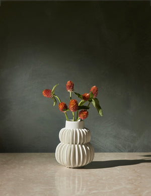 Delilah white ceramic vase featuring two rows of half-moon discs fanned around a tapered body with flowers inside of it