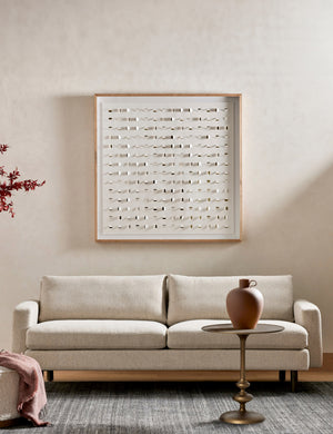 Caratto round matte brass finish metal side table styled with a terracotta vase and light colored sofa.