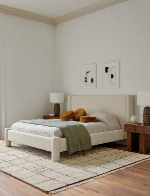 Ivory and ochre Irregular Grid Rug by Sarah Sherman Samuel lays in a bedroom with a natural linen framed bed and a ripple accent chair