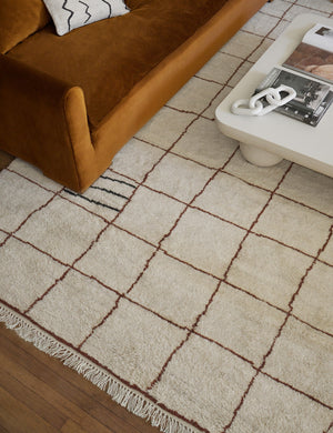 Almarine white marble chain decor sits on a sculptural white coffee table above a checkered ochre and cream rug