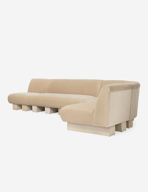 Angled view of the Lena right-facing beige velvet sectional sofa with upholstered beam legs