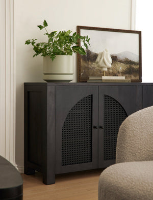 The Hillside Print sits atop a black sideboard next to a large circular planter and a stack of books