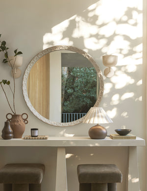 Two Talley modern sculptural wall sconces hung beside an oval mirror above a console table.