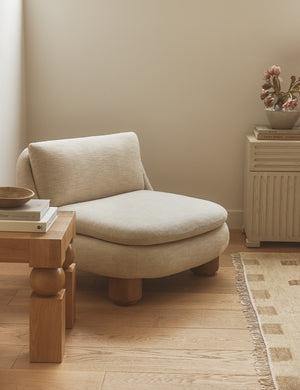 Lozano chunky low-profile armless accent chair styled in the corner of a bedroom.