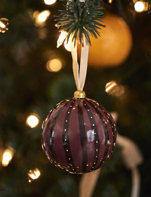 Joelle paper mache ornament hanging on a christmas tree branch