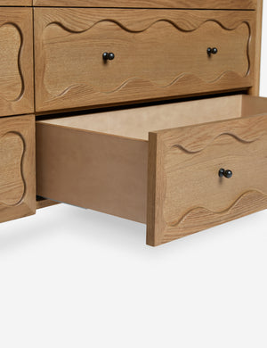 Close up view of the open bottom drawer of the Fontaine wavy detailing solid oak 6-drawer dresser by Aimee Song