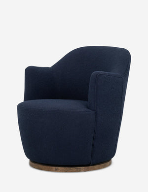 Angled side view of Margie rounded barrel swivel accent chair in navy