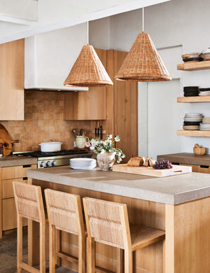 Angled view of the Maritza armless light wood and woven seagrass coastal style counter stool.
