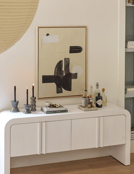 #size::24--x-32- #size::30--x-40- #size::40--x-54- | The In Pursuit Print hangs on a white wall above a white sideboard with stone candle sticks, a bar set, and a stack of books