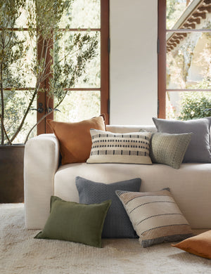 The dusty blue, burnt orange, and olive arlo linen pillows sit together on a plush ivory rug and a natural linen sofa