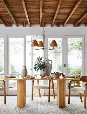 Elvia oval rattan stacked leg dining table with a rattan chandelier hanging above.
