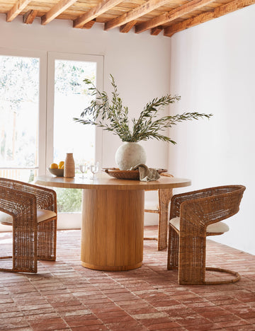 #color::natural | Elvia round rattan stacked leg dining table styled with rattan barrel back dining chairs.