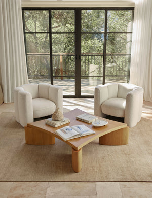 The Heritage wheat rug lays in a living space with floor to ceiling french doors and two boucle accent chairs