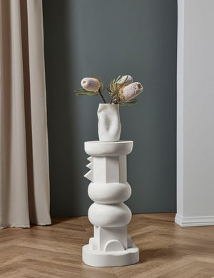 The Toivo short pedestal stands in a room with a sculptural vase sitting atop it