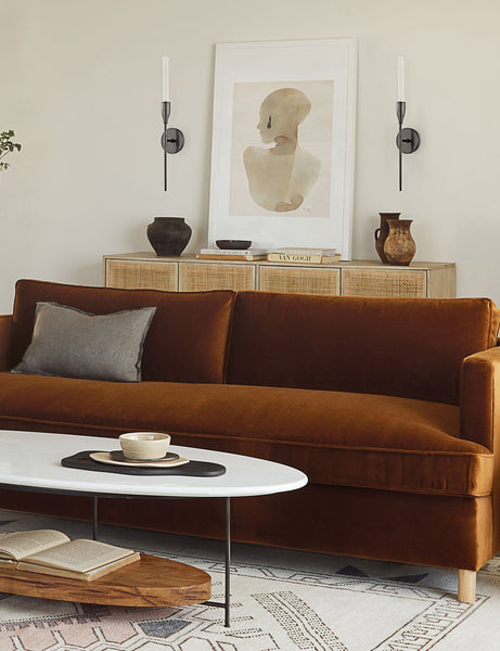 #color::white #size::32.25--x-47.25- #size::38.25--x-56.25- | The Sara singh back drop portrait neutral toned wall art by Stampa sits in a living room atop a woven sideboard with a cognac velvet sofa and a geometric rug