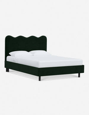 Angled view of Clementine emerald velvet platform bed with undulating lined headboard