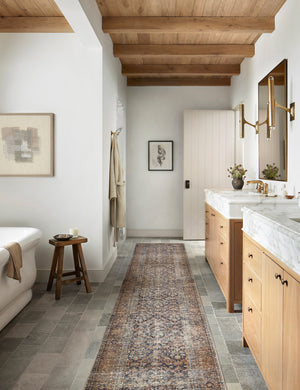 Billie Rug in ink and salmon by Amber Lewis x Loloi in its runner size lays in a bathroom with his and hers sinks and a white bathtub
