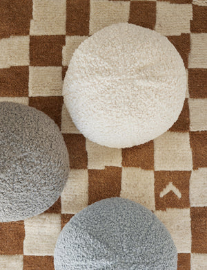 Bird’s-eye view of the Ivory Bouclé Ball Pillow by Sarah Sherman Samuel on a ochre and white patterned rug