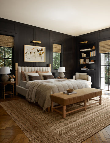 #showall::39490240315491 | The Ambleside natural linen bed sits atop a patterned rug in a room with accented black wooden walls and a orange linen bench