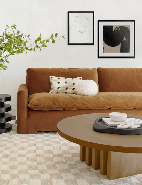 #style::lumbar| Irregular Dots Ivory Lumbar Pillow by Sarah Sherman Samuel sits on a cognac velvet sofa that is atop a beige and white checkboard rug