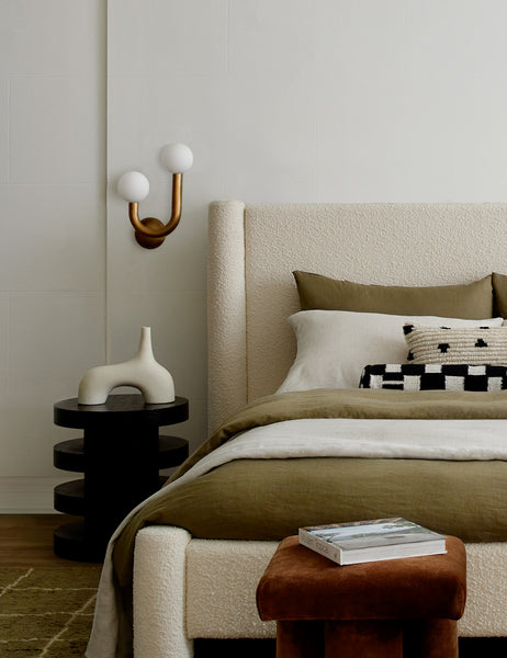 #showall::40084267434083 I| Natural-brass left-facing Happy Sconce by Regina Andrew is hung to the left of a boucle framed bed above a three tiered bed stand