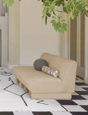 Khaki gray Bouclé Ball Pillow by Sarah Sherman Samuel sits on a neutral armless sofa atop a black and white checkerboard floor