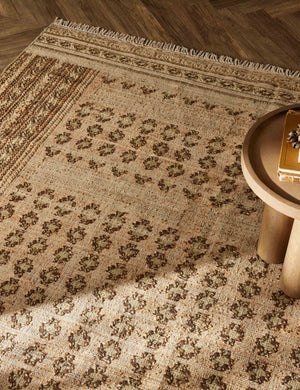Close-up of the Keziah moss rug under a round side table with pedestal legs