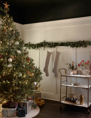 Evander brass frame and white marble bar cart styled next to a christmas tree and railing with stockings.