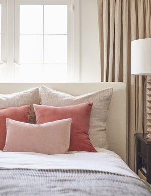 Charlotte rosewater pink square velvet pillow sits on a neutral linen framed bed with striped linens and dark pink throw pillows