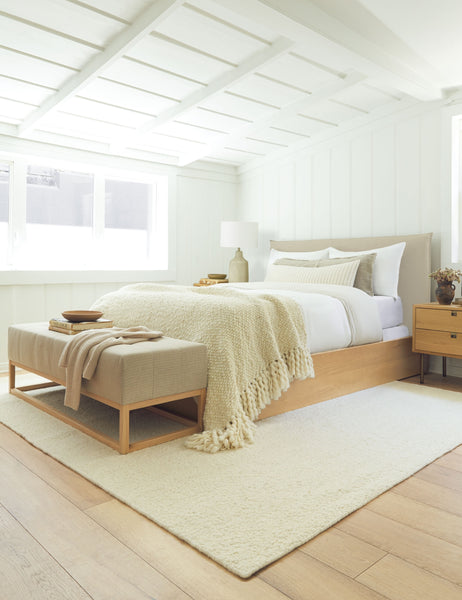 #showall::39490224291939 | The Nia natural linen bed sits atop an ivory rug with a linen bench under a white sloped ceiling