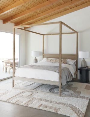 Canyon Terracotta Long Lumbar Pillow sits on a wooden canopy bed in a room with a cream and neutral geometric rug and a wooden ceiling