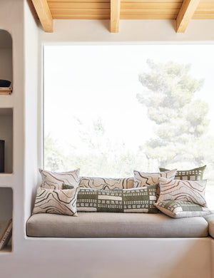 Canyon Terracotta Square and Lumbar Pillows sit on a bench with other canyon throw pillows in front of a large window