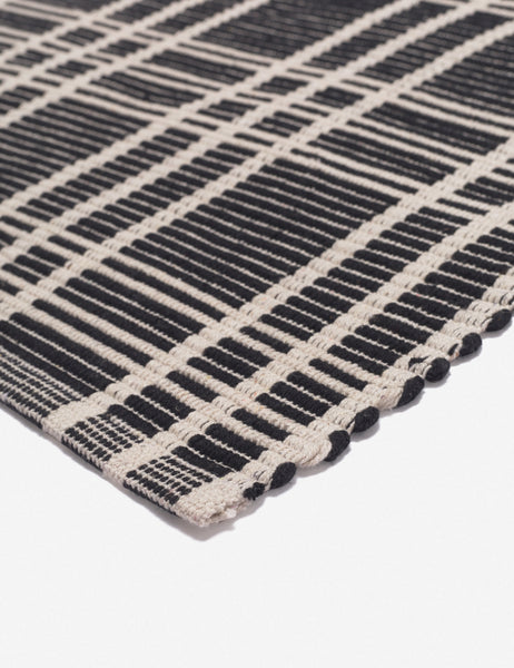 #size::1-9--x-2-10- #size::2--x-5- | Corner shot of the Rika black and white cotton machine washable mat with checkerboard pattern