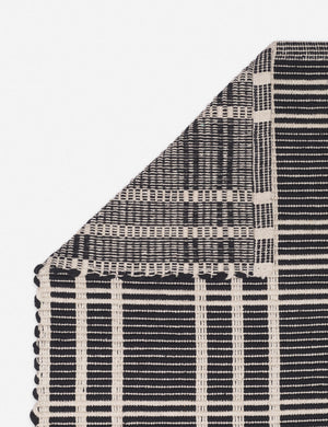Corner shot of the Rika black and white cotton machine washable mat with checkerboard pattern